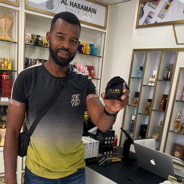 Man taking a selfie in front of a store counter with 'pearl fragrances' branding.